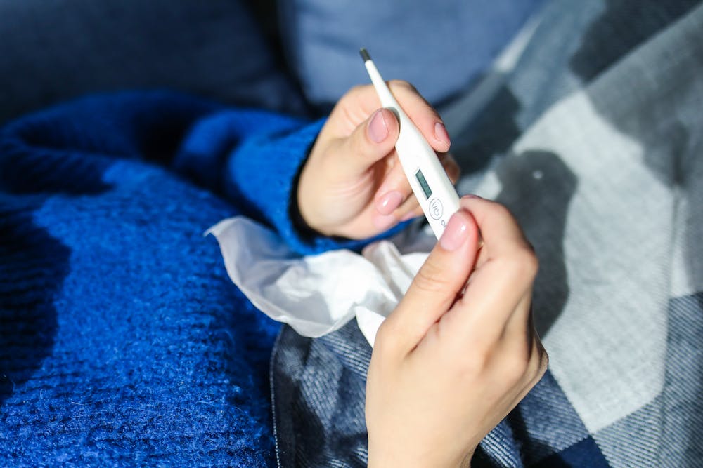 Photo of two hands holding a thermometer and tissue. Photo by  Polina Tankilevitch